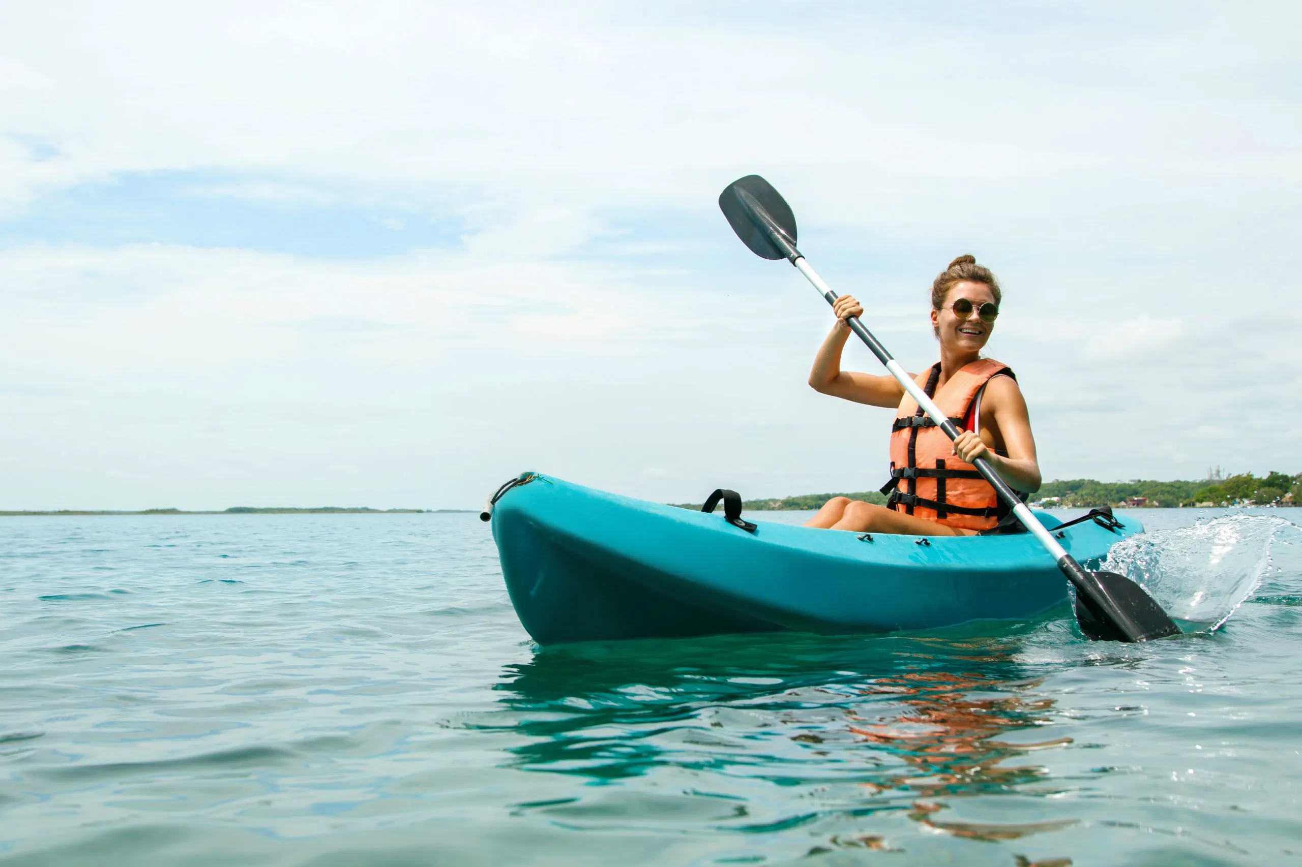 Happy young woman kayaking on the lake