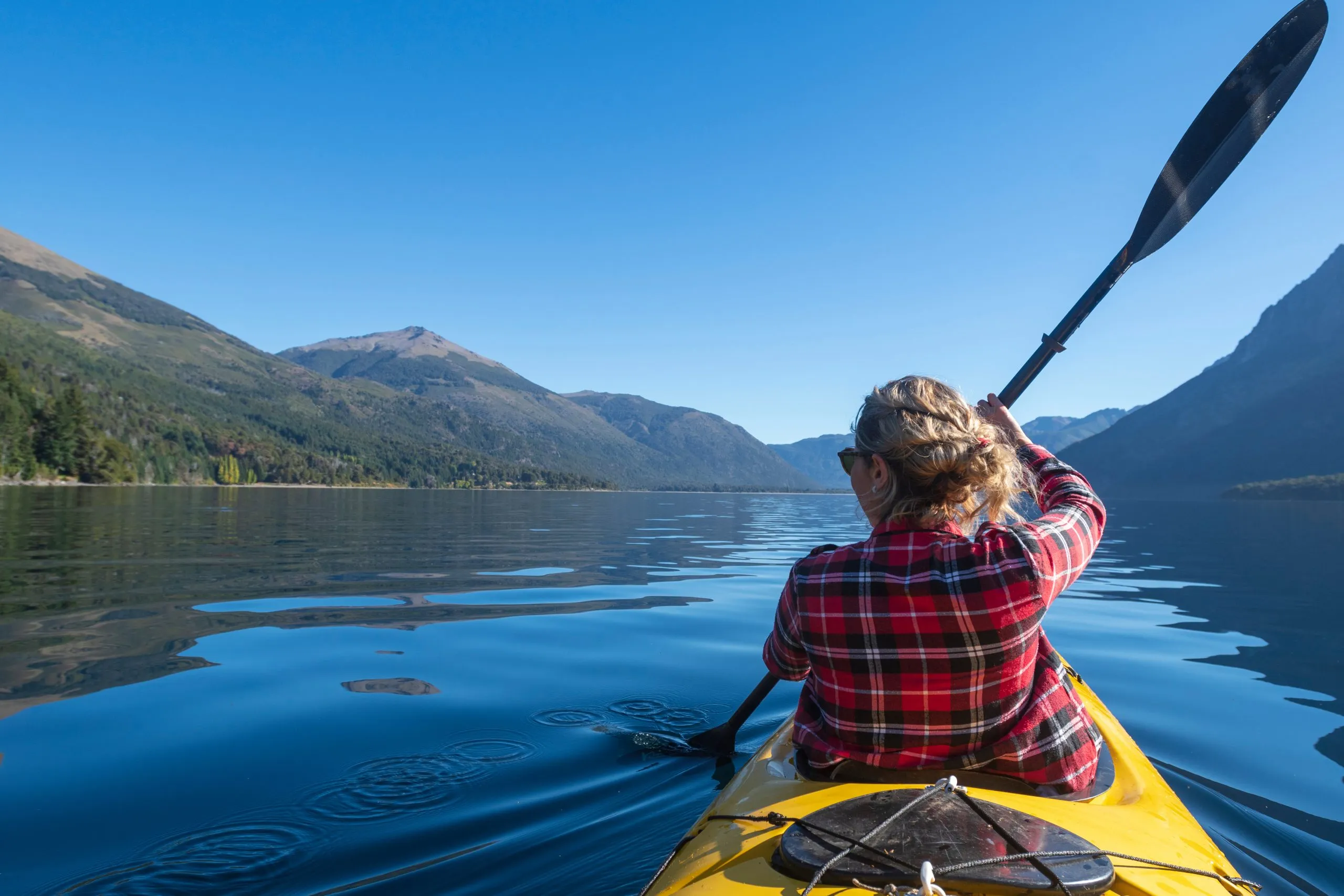 Young woman paddling a kayak touring the lakes of the National Park. Patagonia, Argentina.